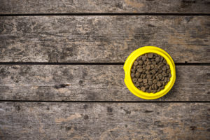 bowl of dry dogs food on wooden floor UKRP2U3 Pepper Paws Pepper Paws Hundefutter von PepperPaws